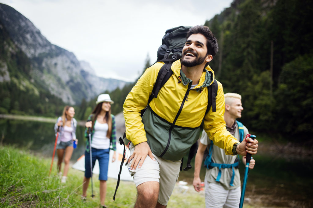 Group of young friends hiking in countryside. Multiracial happy people traveling in nature