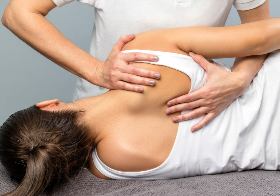 Close up of detail of female physiotherapist doing shoulder blade treatment on patient.