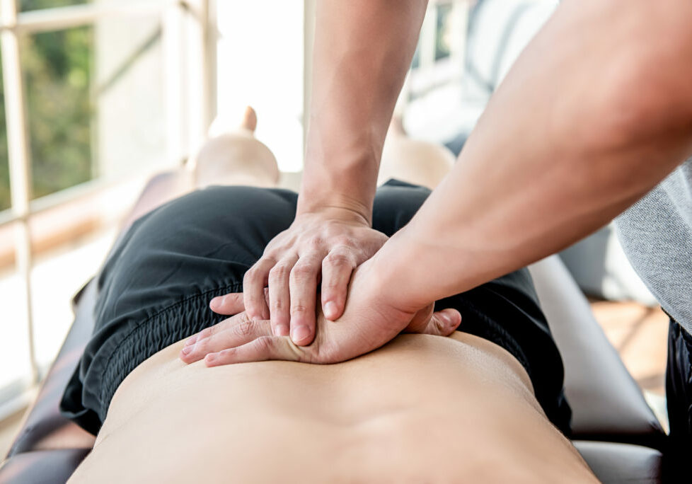 Therapist giving lower back sports massage to athlete male patient